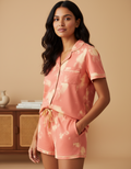Woman wearing a pink tie-dye pajama set against a beige background
